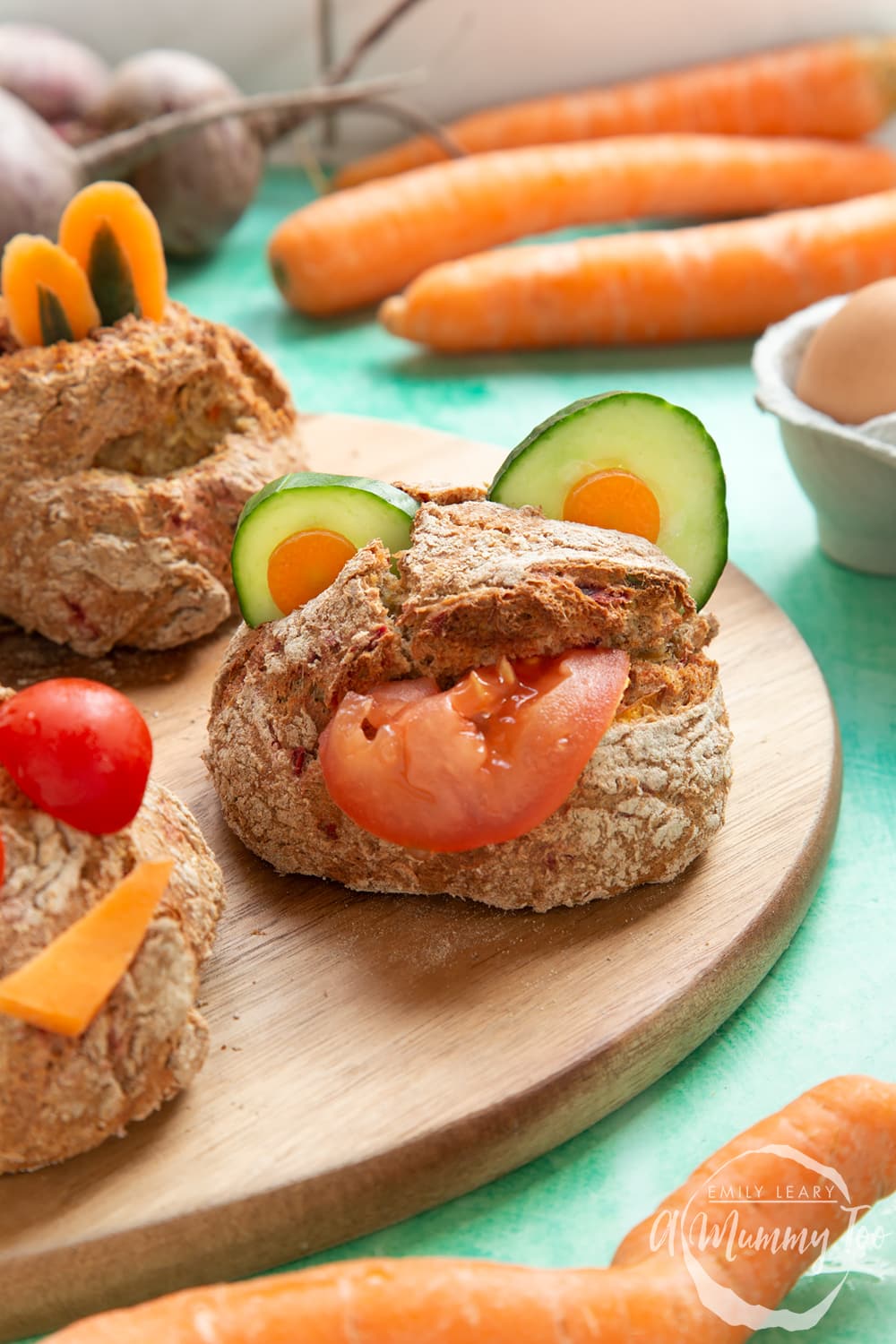 Vegetable soda bread rolls recipe - rolls arranged on a board, each decorated with vegetable slices to look like monsters.