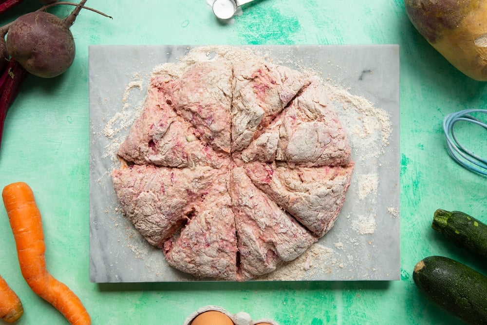 Vegetable soda bread rolls recipe - the pink dough round cut into eight pieces on the board.