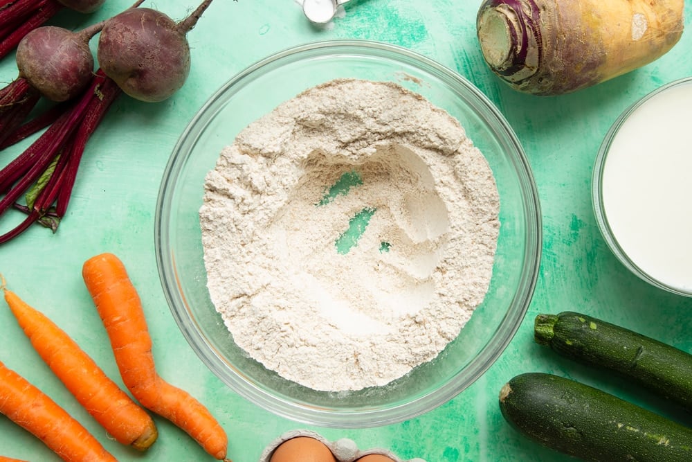 Vegetable soda bread rolls recipe - a bowl with wholemeal flour and baking powder with a well in the middle.