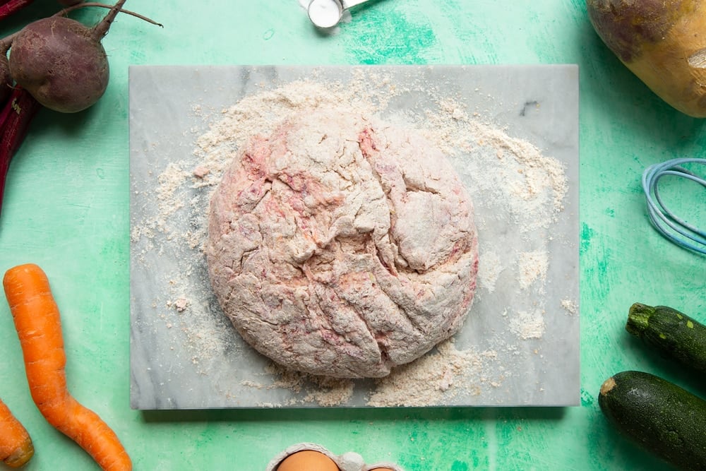 Vegetable soda bread rolls recipe - the pink dough formed into a round on the board.