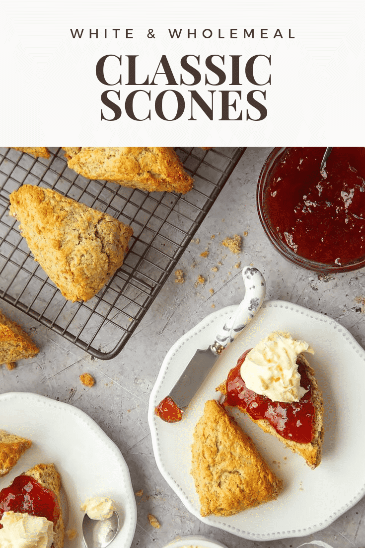 Overhead shot of a classic white and wholemeal scone on a decorative plate covered in jam and cream. At the side there's a decorative butter knife with some left over jam. At the top of the image there's some text describing the image for Pinterest. 