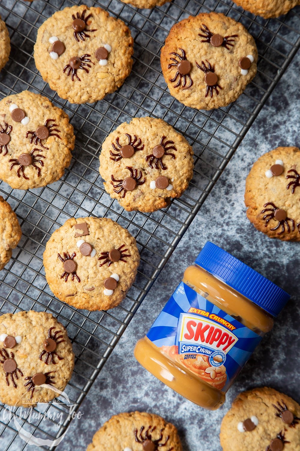 Halloween peanut butter spider cookies cooling on a wire rack. A jar of Skippy Super Crunchy Peanut Butter is shown to one side.