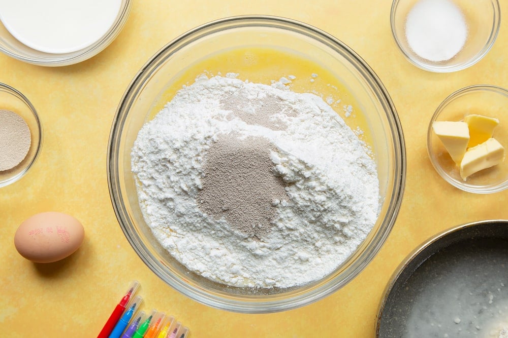 Flour and yeast added to a mixture of egg, tangzhong, sugar, warm milk and warm butter in a large bowl.