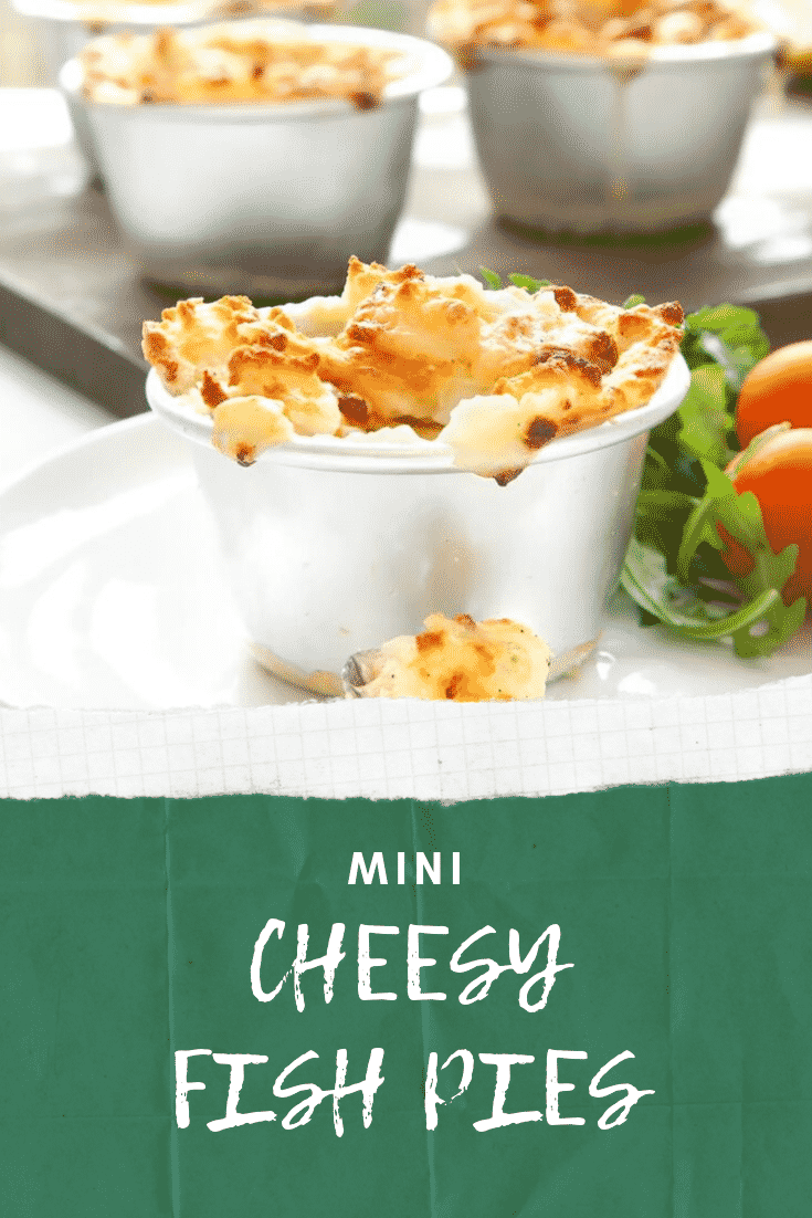 Close up shot of an indervidual mini cheesy fish pie on a white plate with a side of salad. At the bottom of the image there's some white text on a green background describing the image for Pinterest. 