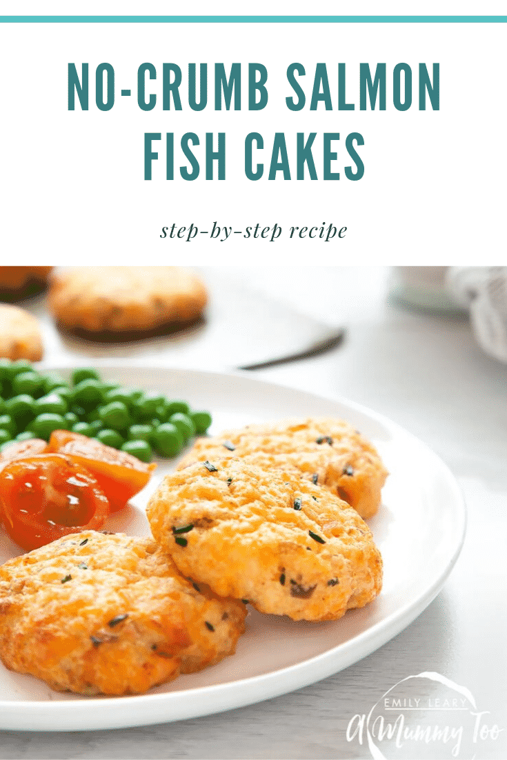 Close up of three salmon fish cakes on a white plate with vegetables. In the background you can see some additional salmon fish cakes on a baking sheet. At the top of the image there's some text describing the image for Pinterest. 