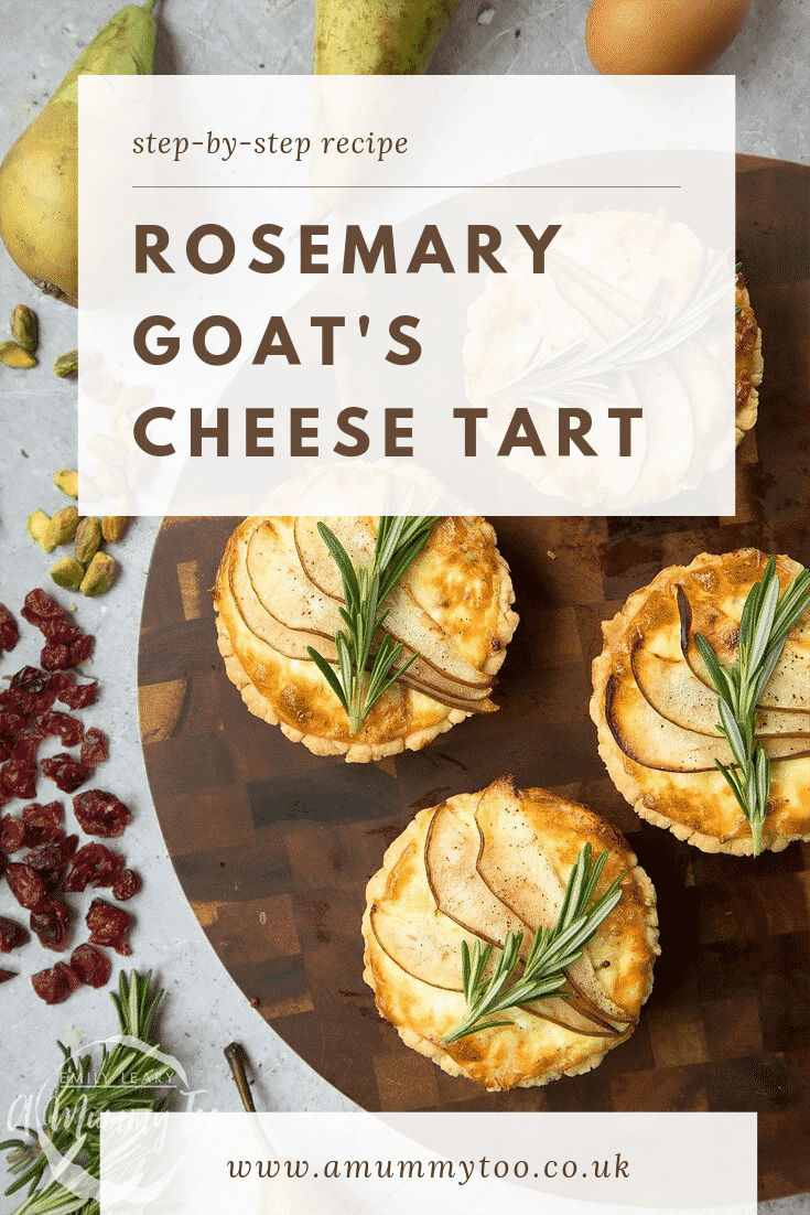 Overhead shot of four rosemary goat's cheese tarts on a decorative wooden circular board with different ingredients required for the recipe scattered at the side.