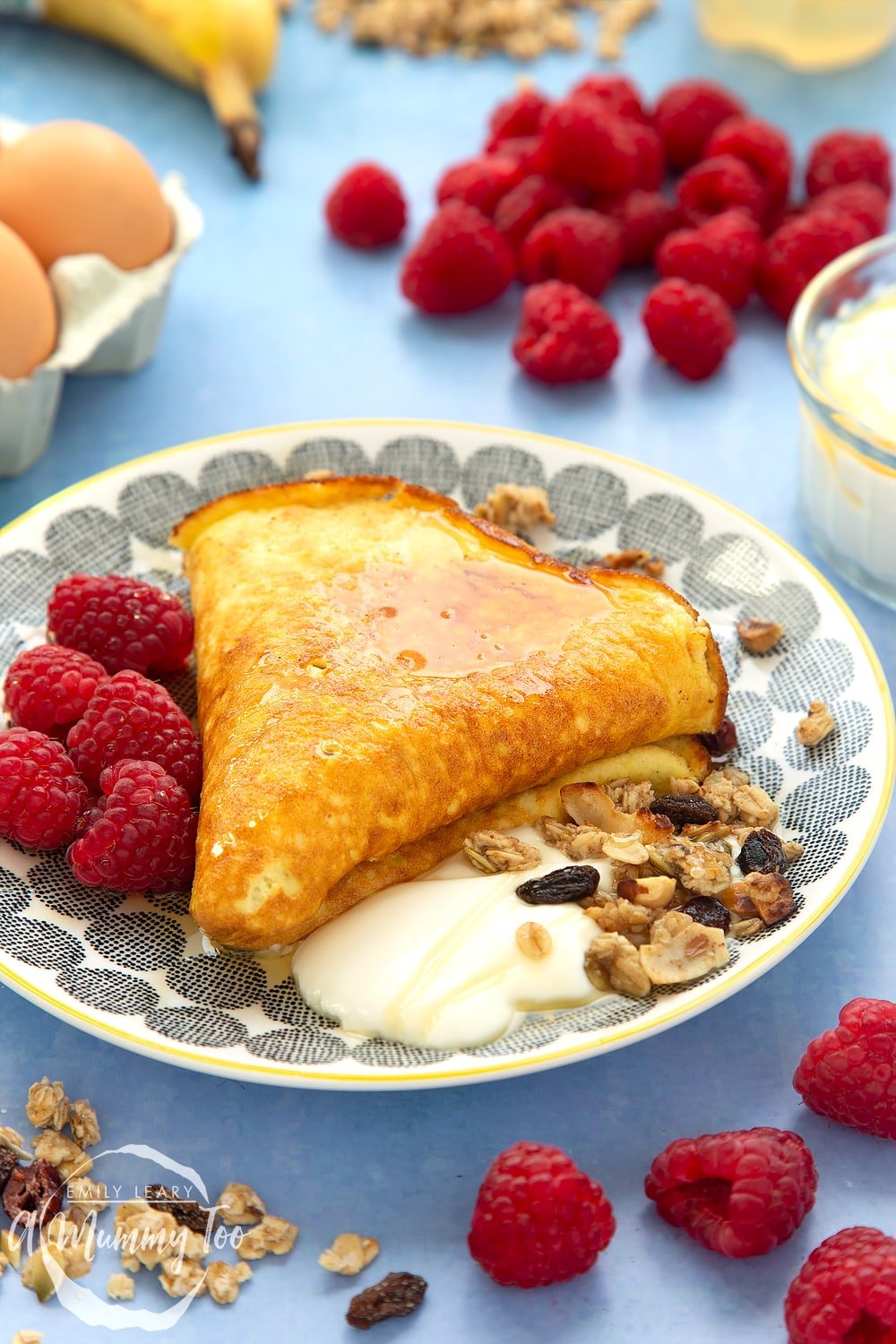 Sweet breakfast omelette, folded and served to a plate with yogurt, granola and raspberries