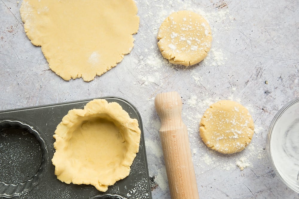 yellow like coloured pastry dough balls squashed flat on a surface and one put into a pastry tin.