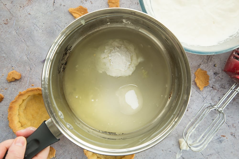 Arrowroot, lemon, sugar and water in a large saucepan held by a hand.