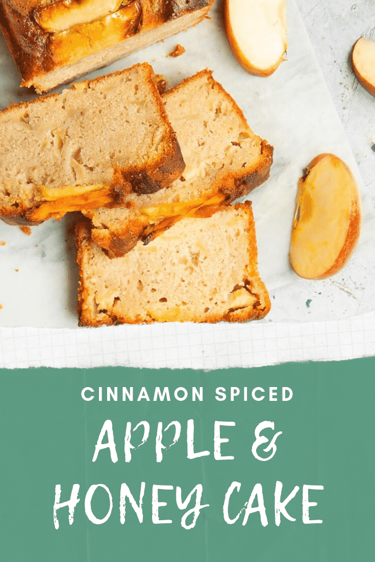 Sliced apple and honey cake served on a white table with some sliced apples on the side. At the bottom of the image there is some text describing the image for Pinterest.