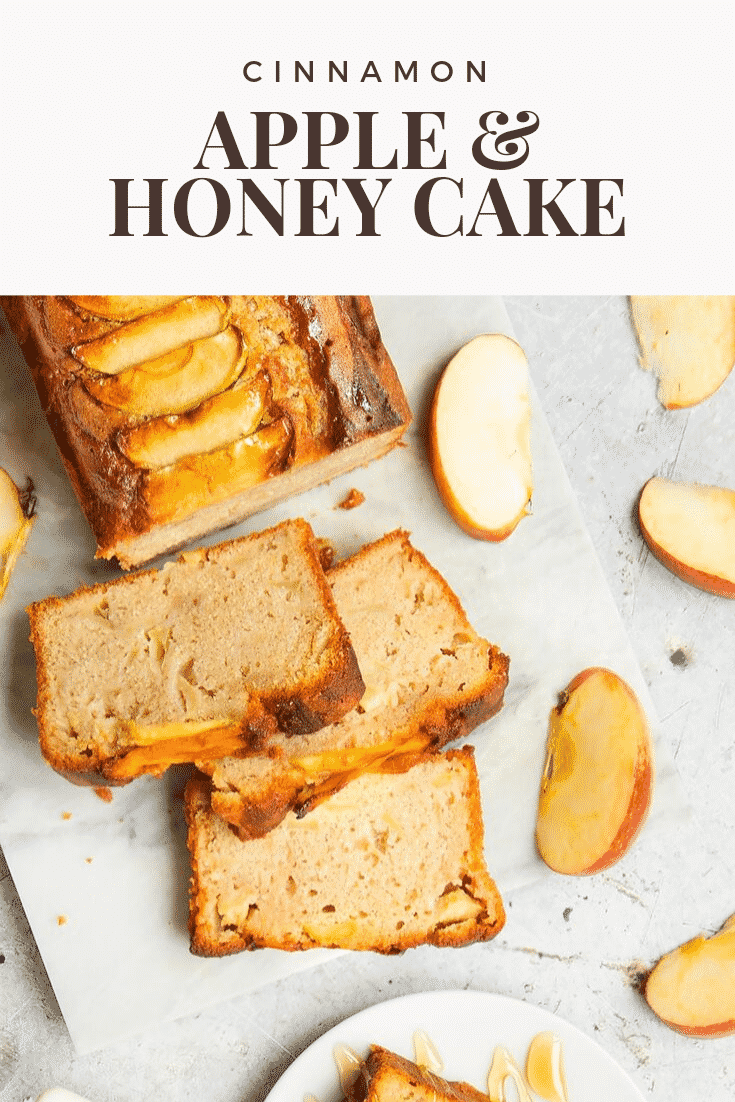 Overhead shot of the sliced cinnamon apple and honey cake on a white table. At the top of the image there's some brown text describing the image for Pinterest. 