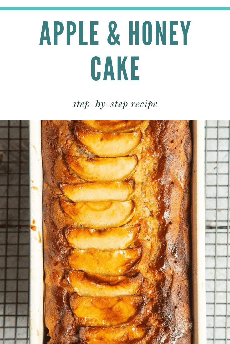 Close up overhead shot of the apple and honey cake inside a tin cooling on a wire rack. At the top of the image there is some teal text describing the image for Pinterest. 