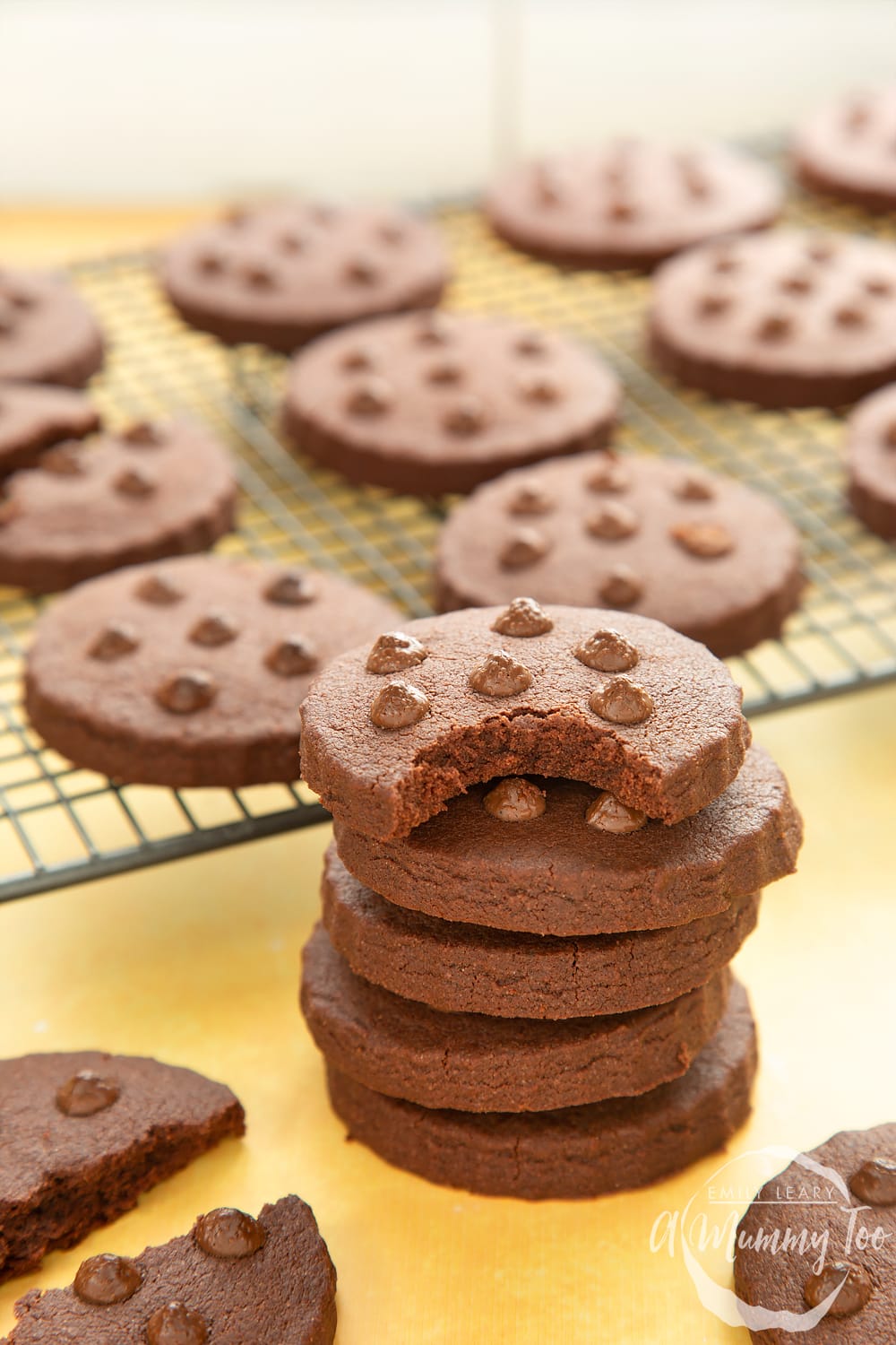 A stack of chocolate shortbread cookies. The top cookie has a bite out of it.