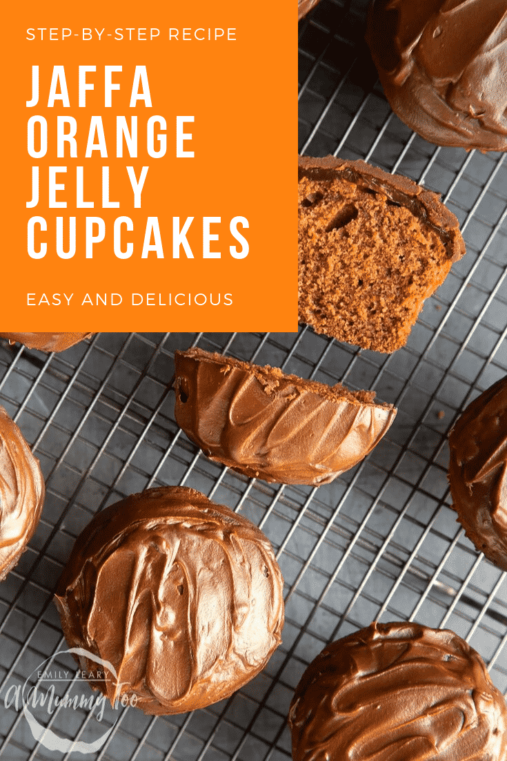 Overhead shot of the finished jaffa orange jelly cupcakes cooling on a wire rack. In the top left hand corner there's some white text on an orange background describing the image for Pinterest.