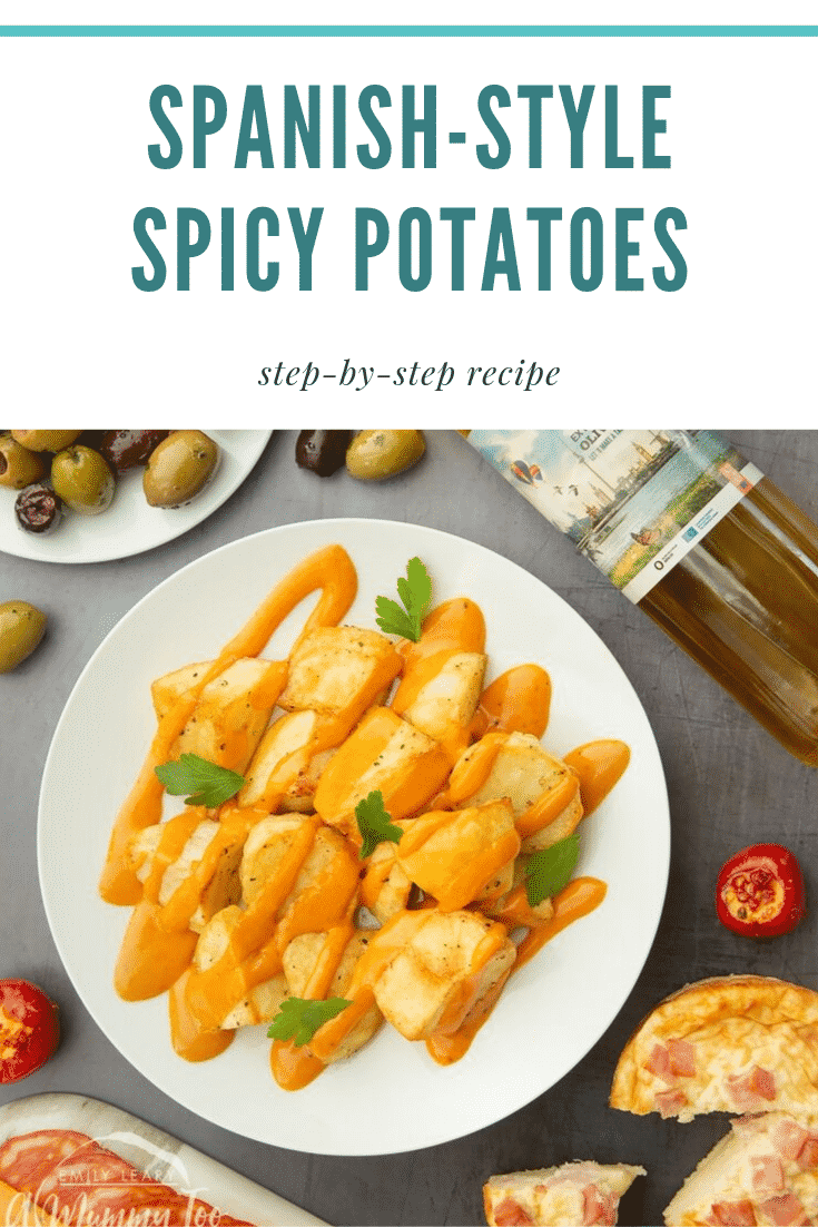 Overhead shot of a portion of Spanish-style spicy potatoes on a white plate which is sat on a black / grey table. At the top of the image there's some teal text describing the image for Pinterest. 