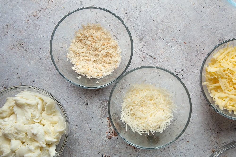 Overhead shot of four small bowls of cheese. 