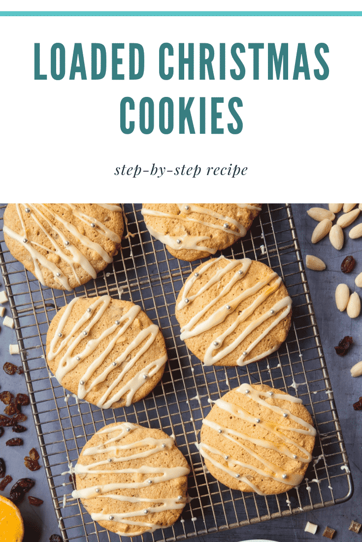 Six loaded Christmas cookies on a cooling rack on top of a dark grey counter top. There's some text at the top of the image describing the image for Pinterest.