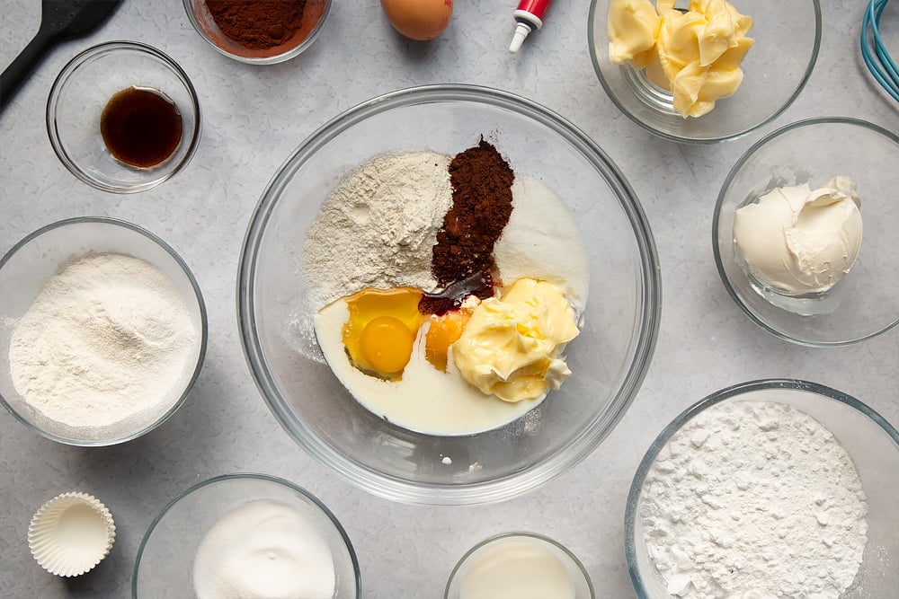 Overheadshot of multiple bowls with ingredients inside required to make the mini red velvet cupcakes with cream cheese frosting.