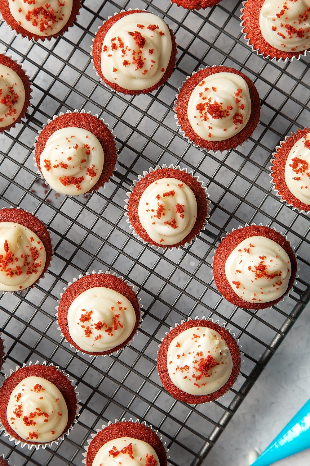 Adding the crumbled red velvet to the top of the mini cupcakes.