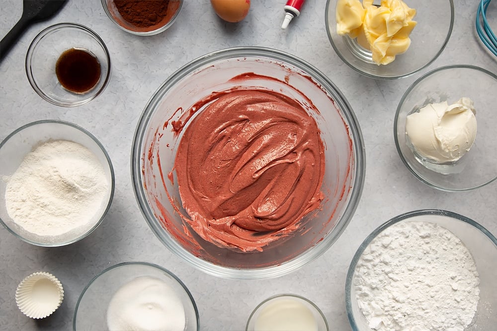 Mixing together some of the ingredients required to make the mini red velvet cupcakes with cream cheese frosting in a glass bowl.