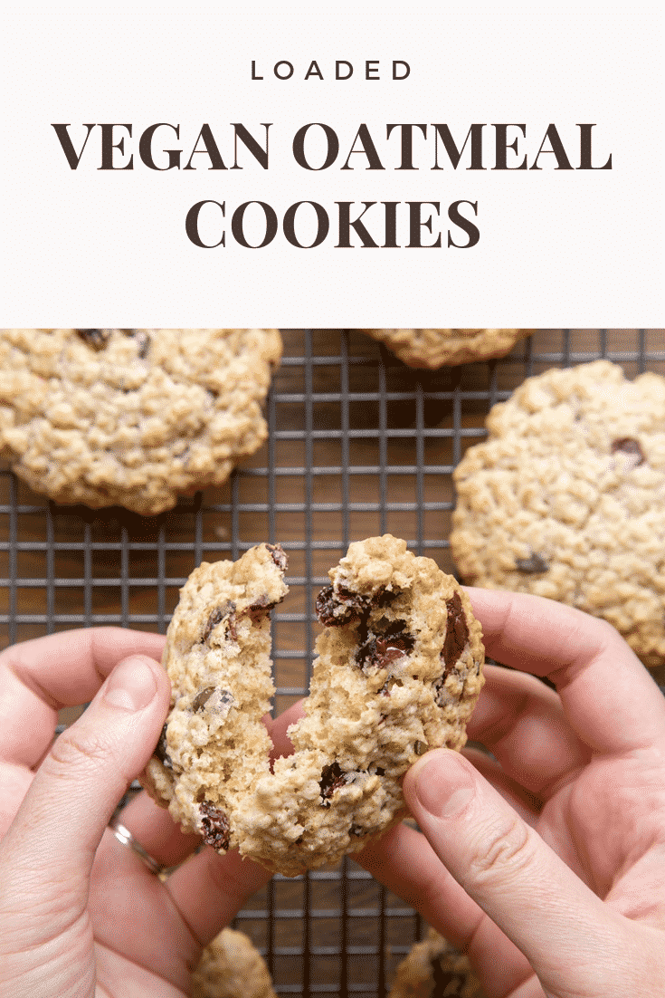 A hand holds a vegan oat cookie and is breaking it open. Caption reads: loaded vegan oatmeal cookies