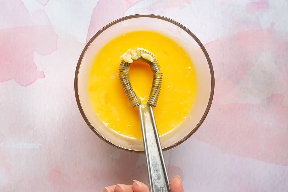 A small bowl containing a small amount of Arroz Doce and beaten egg yolks mixed together