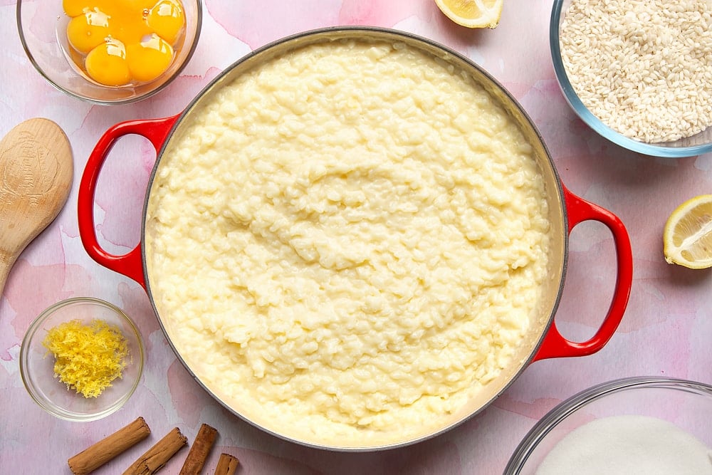 A pan filled with Arroz Doce. Ingredients to make the rice pudding surround the pan.