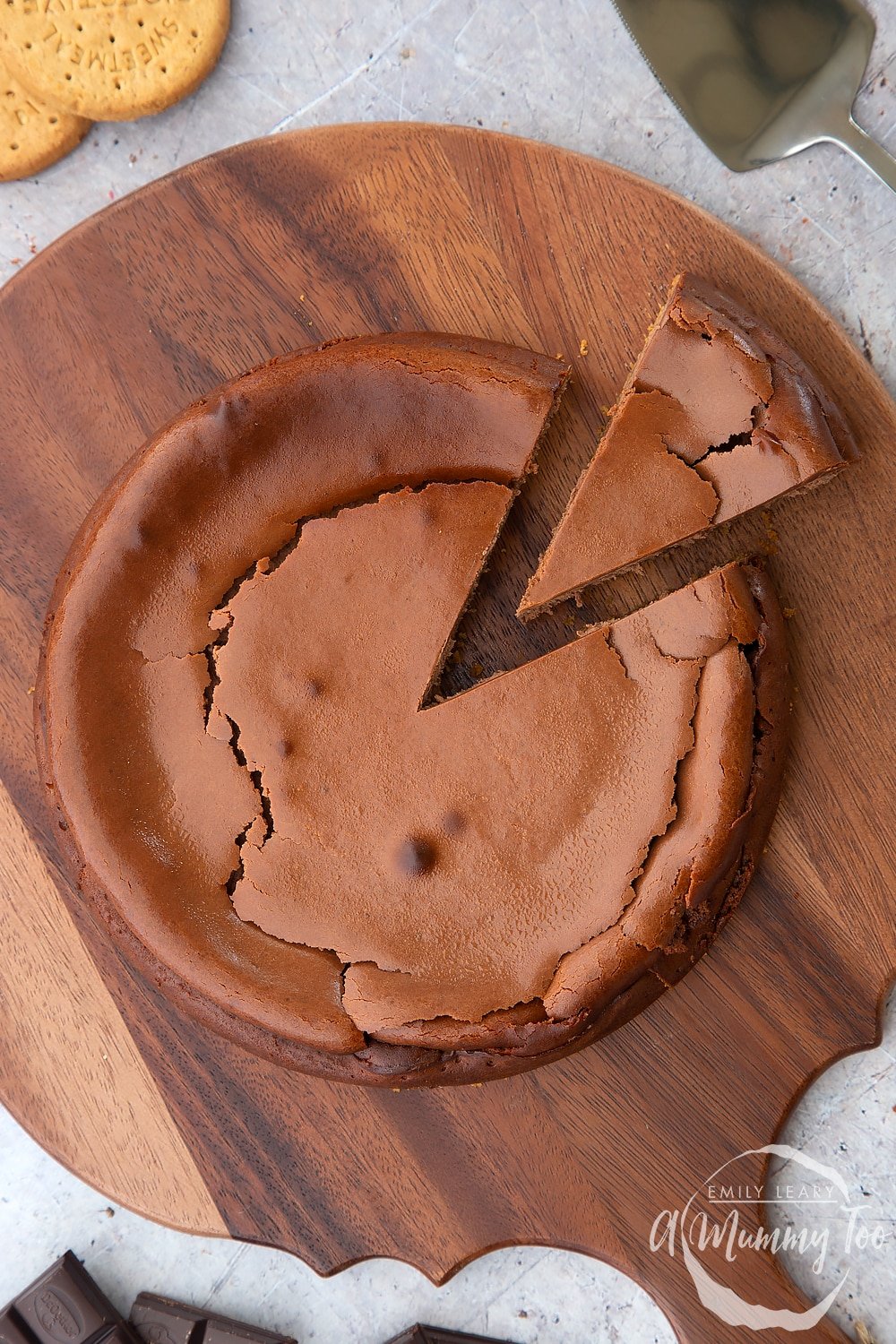 Overhead of the finished bake chocolate cheesecake with a slice cut out. The finished cheesecake sits on a wooden board. 