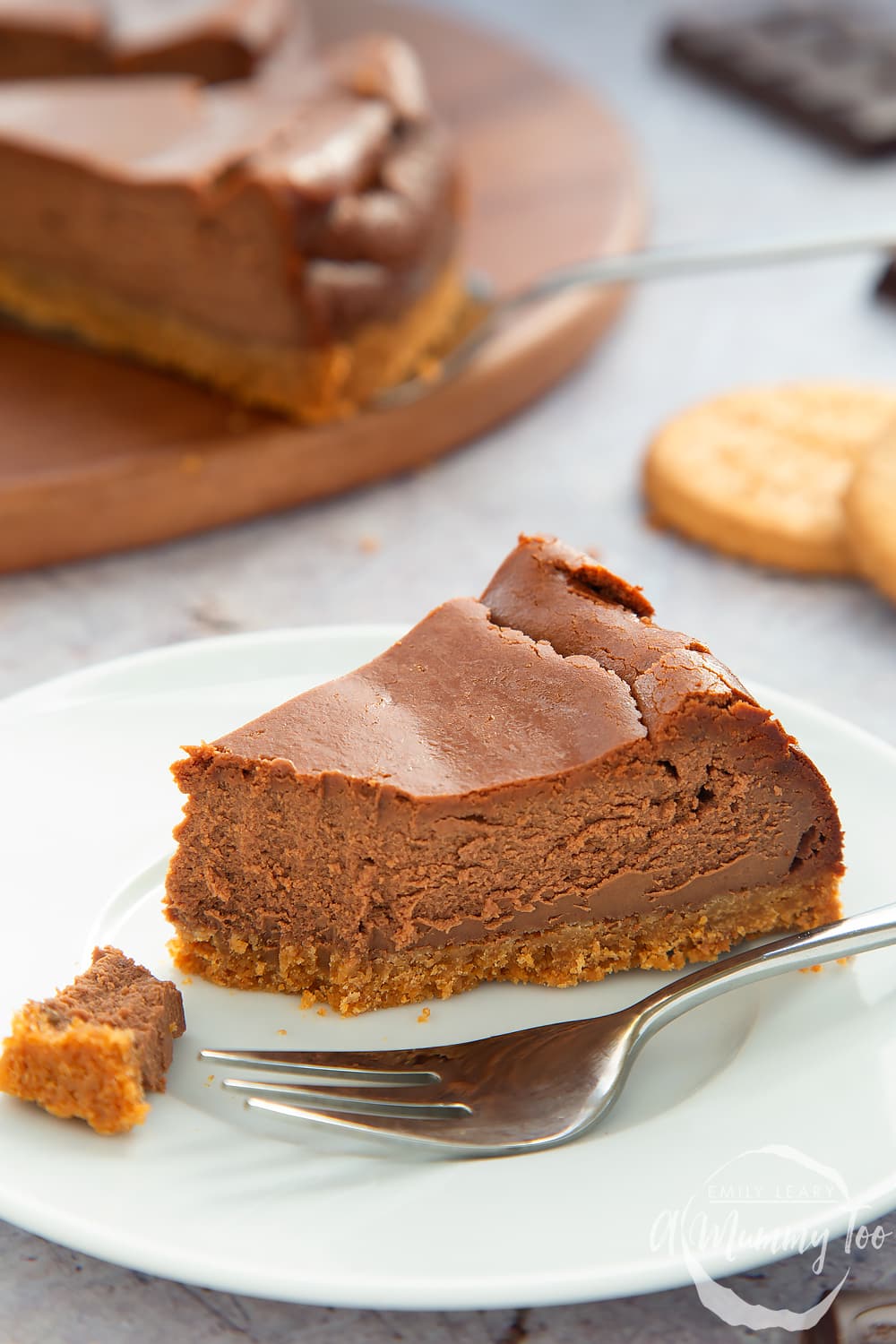 Side on view of the baked chocolate cheesecake slice with a fork on the side on a white plate. 