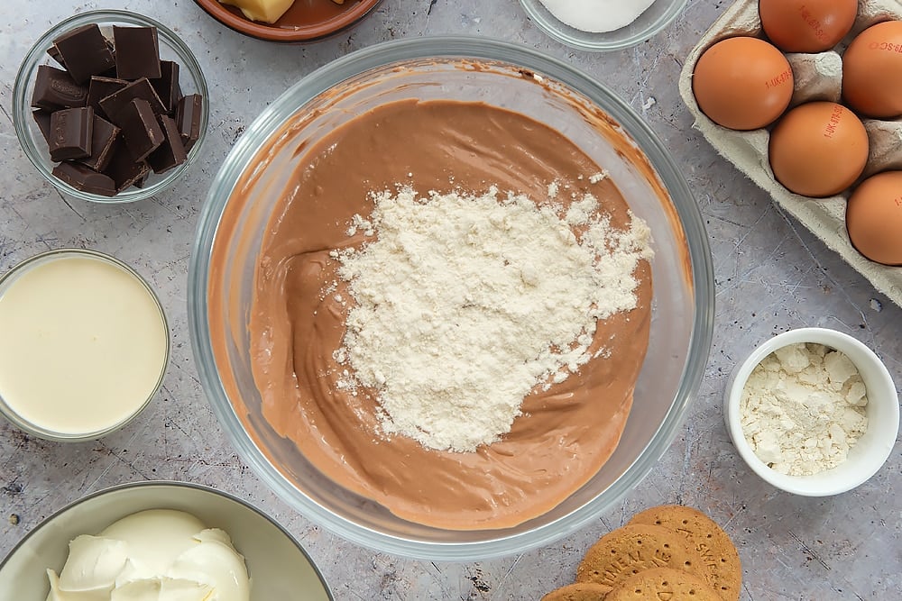 Overhead shot of adding the flour to the chocolate cheesecake mixture. 