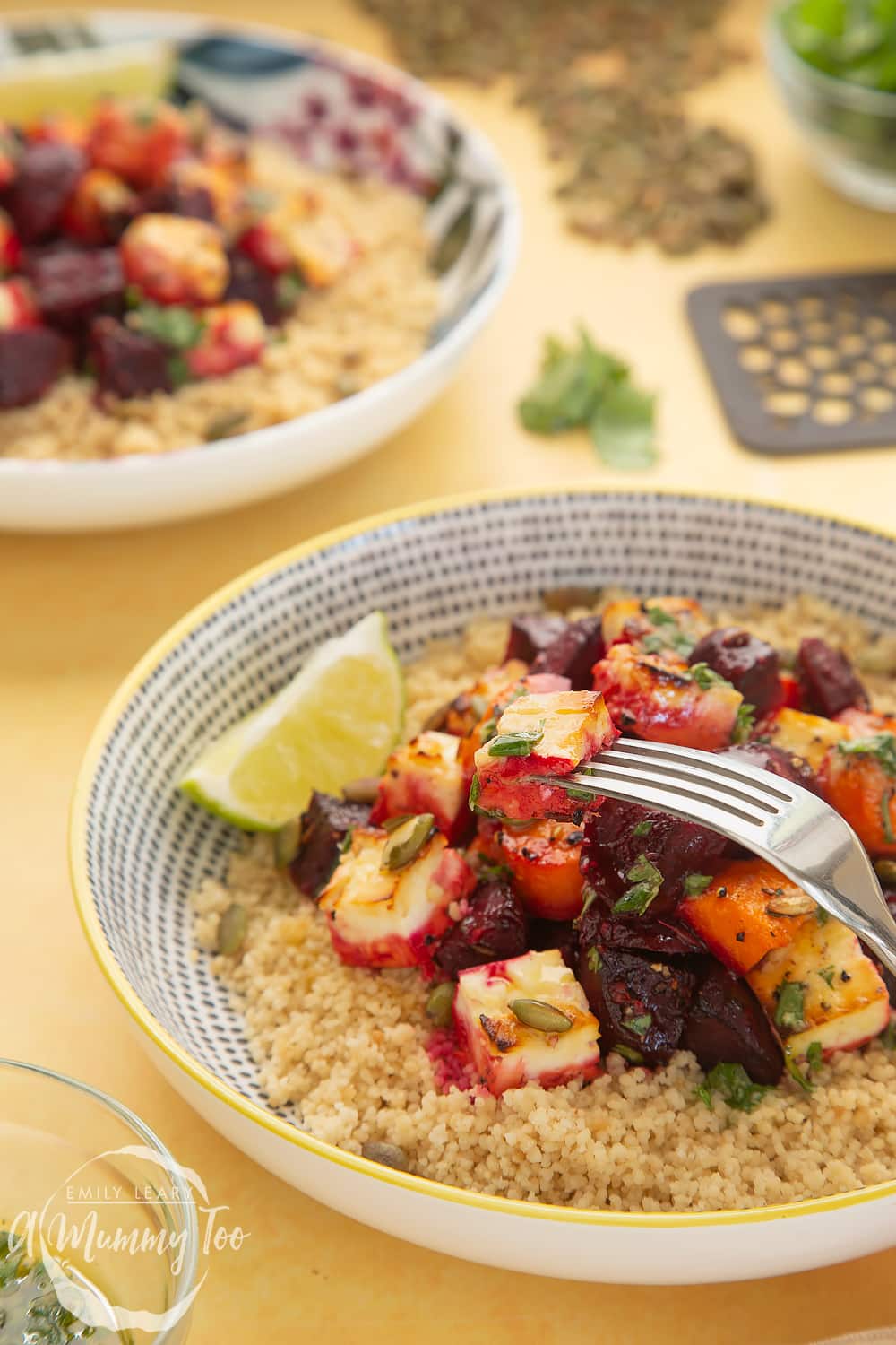 Side on view of a bowl of Beetroot and feta salad with couscous in the background there's an additional bowl of Beetroot and feta salad with couscous. 