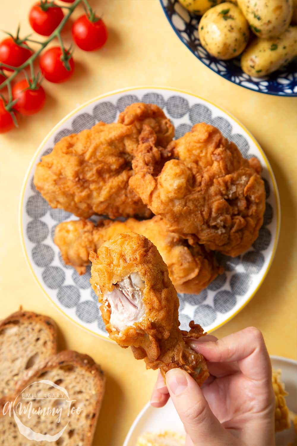 Gordon Ramsay’s buttermilk fried chicken arranged on a plate. A hand holds a well-coated drumstick, with a bite taken out.