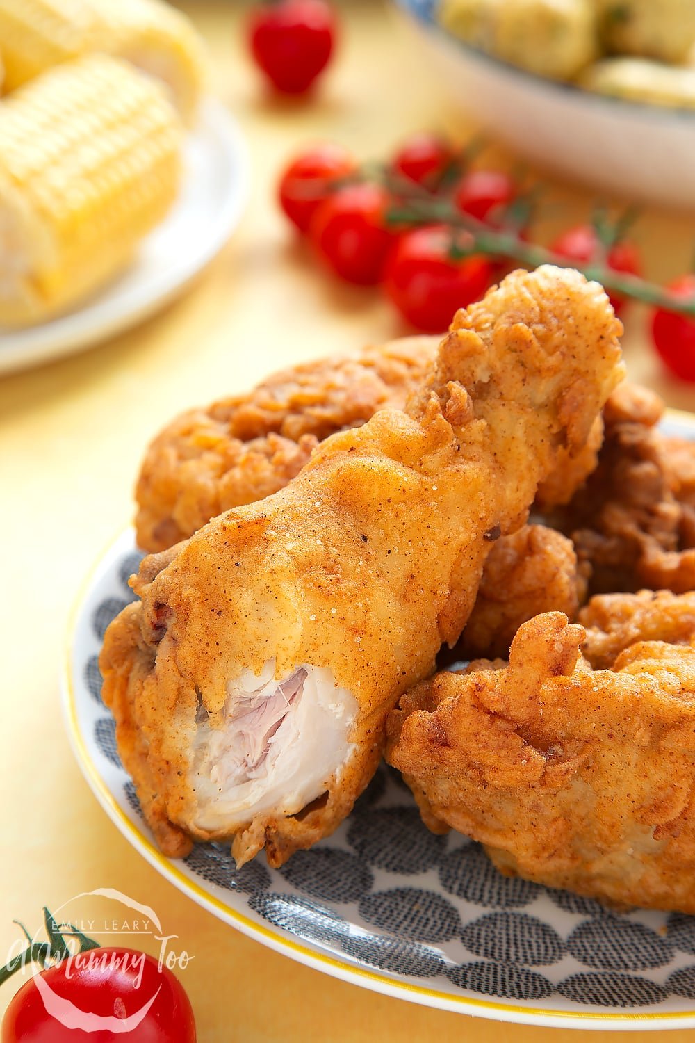 Gordon Ramsay’s buttermilk fried chicken arranged on a plate, a drumstick leaning on the pile, with a bite showing the juicy chicken flesh beneath.