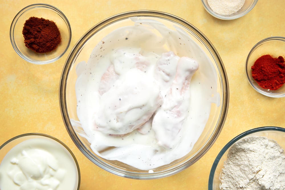 Chicken thighs and drumsticks in a large bowl, tossed with buttermilk, salt and pepper.