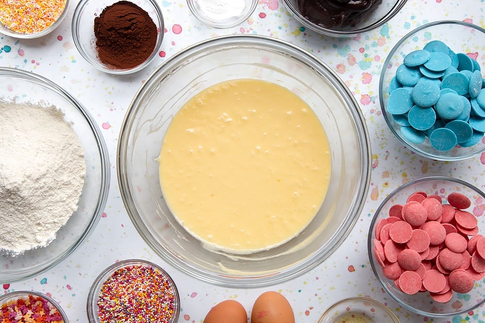 Sukker, smør og egg kremes sammen i en bolle. Ingredienser for å lage en kake pop bukett omgir bollen.
