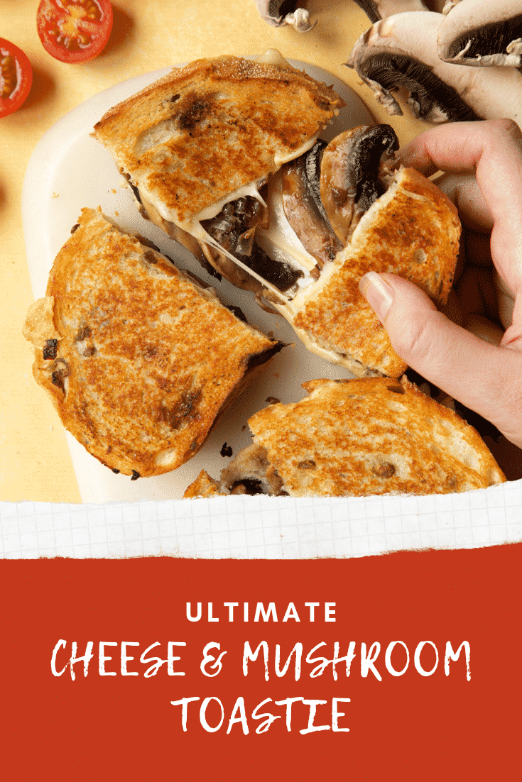 Two Jarlsberg cheese and mushroom toasties are on a serving board, one is being pulled apart so the cheese and mushrooms stretch out between them.