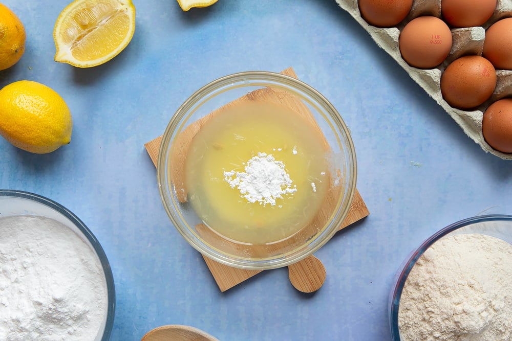 A small glass bowl containing lemon juice and icing sugar.