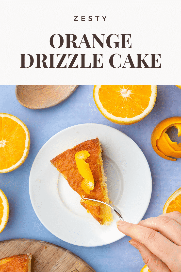 A slice of orange drizzle cake served on a small white plate. A hand holding a fork cuts into the cake. Caption reads: zesty orange drizzle cake