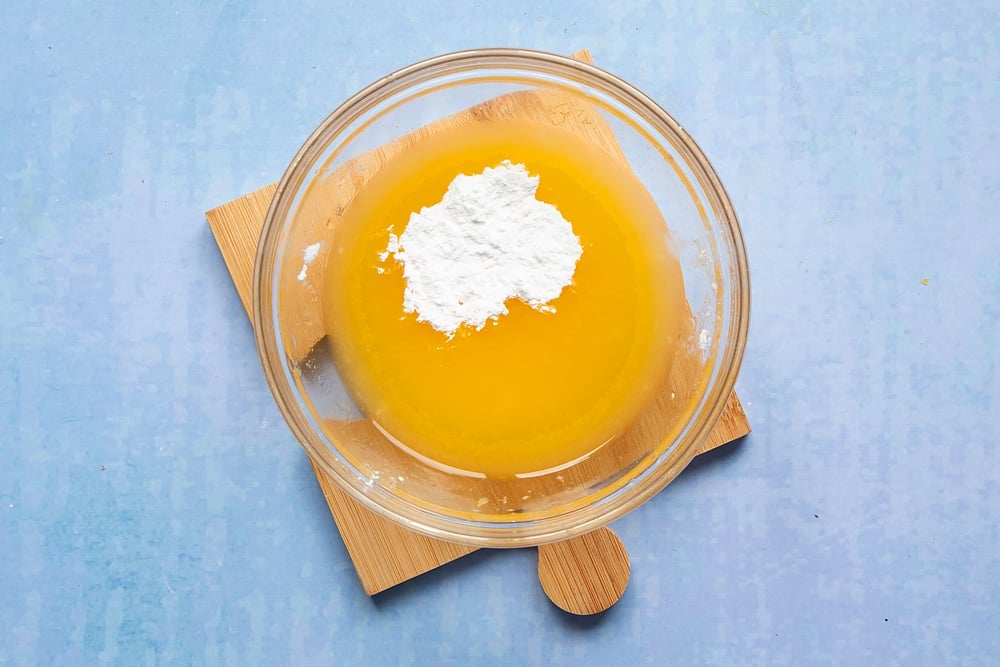 Orange juice and icing sugar in a small glass bowl.