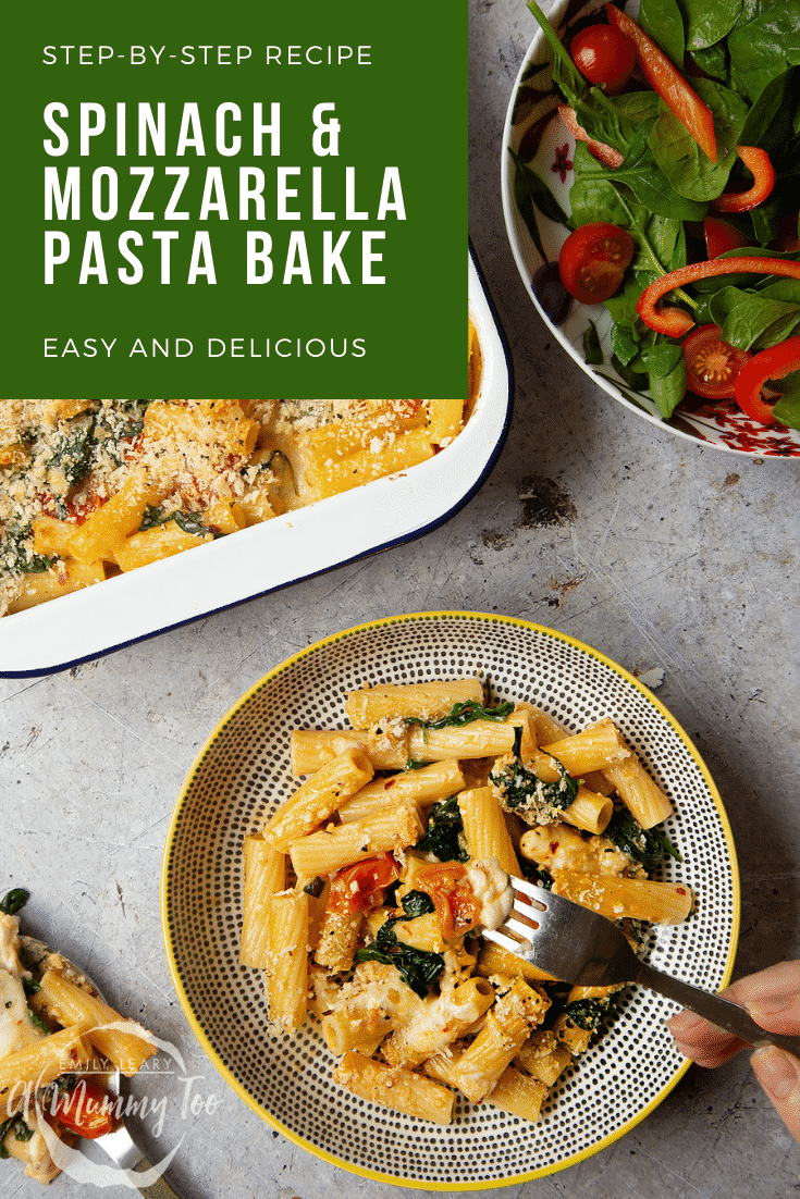 Overhead shot of a decorarive bowl filled with Cherry tomato, spinach and garlic mozzarella pasta bake. Alongside the tray of the remaining bake and a side salad. At the top of the image there's some white text on a green background describing the image for Pinterest. 