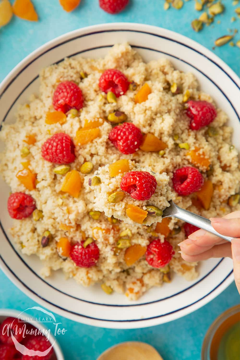 Overhead close up shot of the spoon going into the bowl of sweet breakfast couscous 