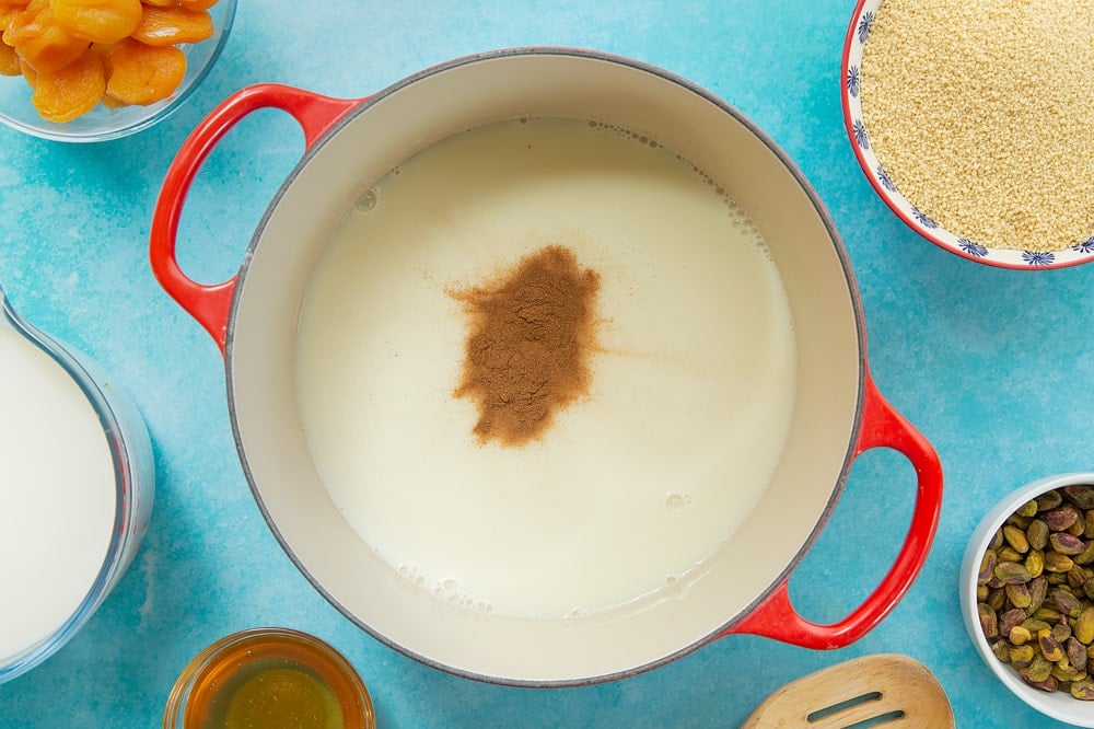 Overhead shot of a red pan with some of the ingredients required to make the sweet breakfast couscous. 