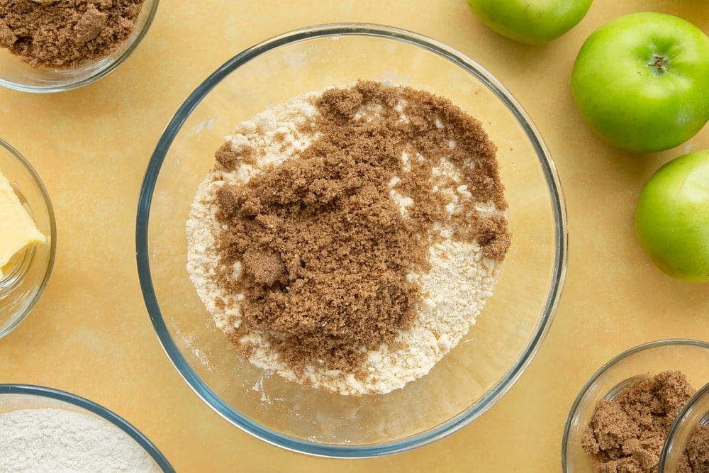 Adding sugar and cinnamon to the mixture for the toffee apple crumble topping. 