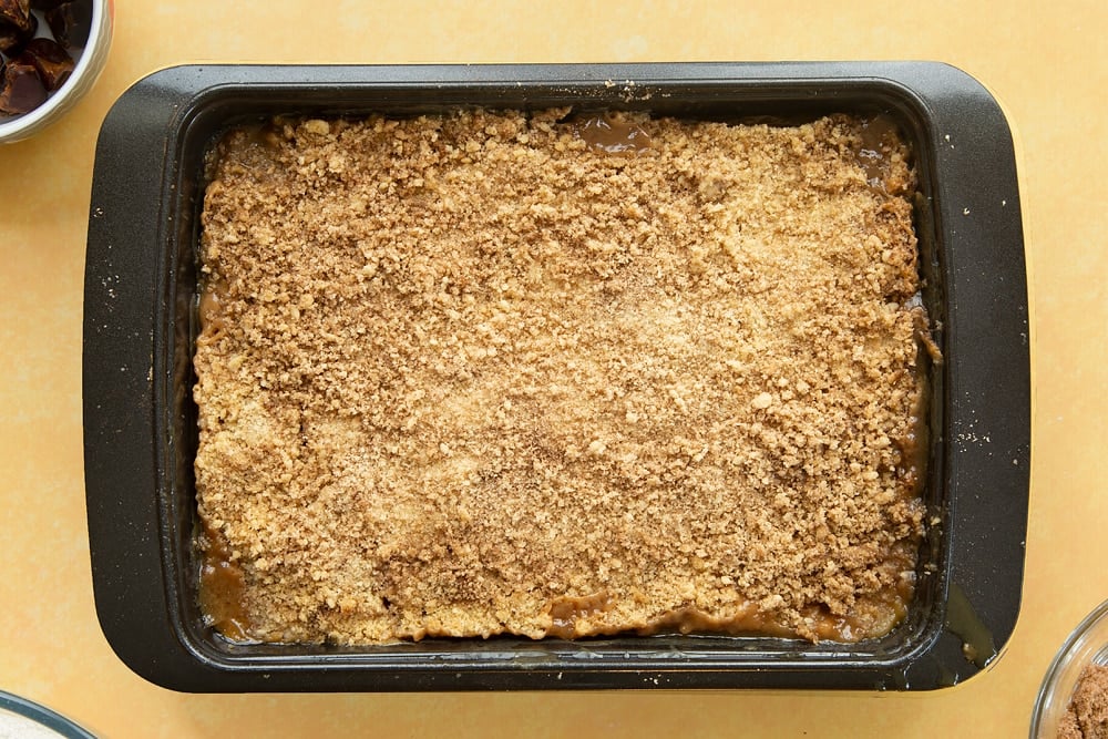 Overhead shot of the finished toffee apple crumble in a pan having been in the oven. 