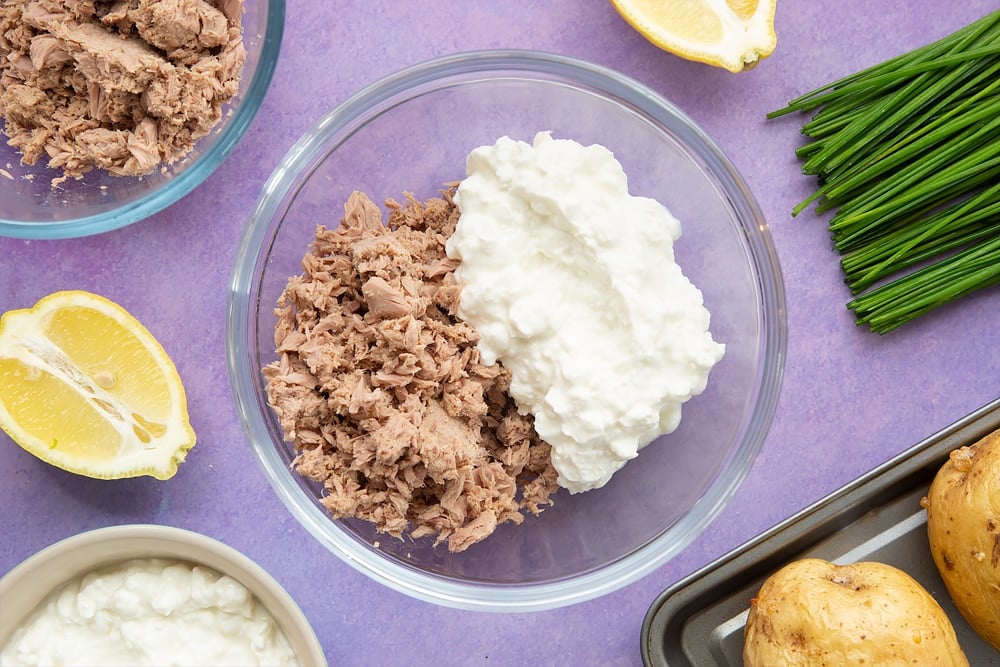 Create the filling for the low-fat tuna cheese jacket potato by mixing together cottage cheese and tuna in a mixing bowl.