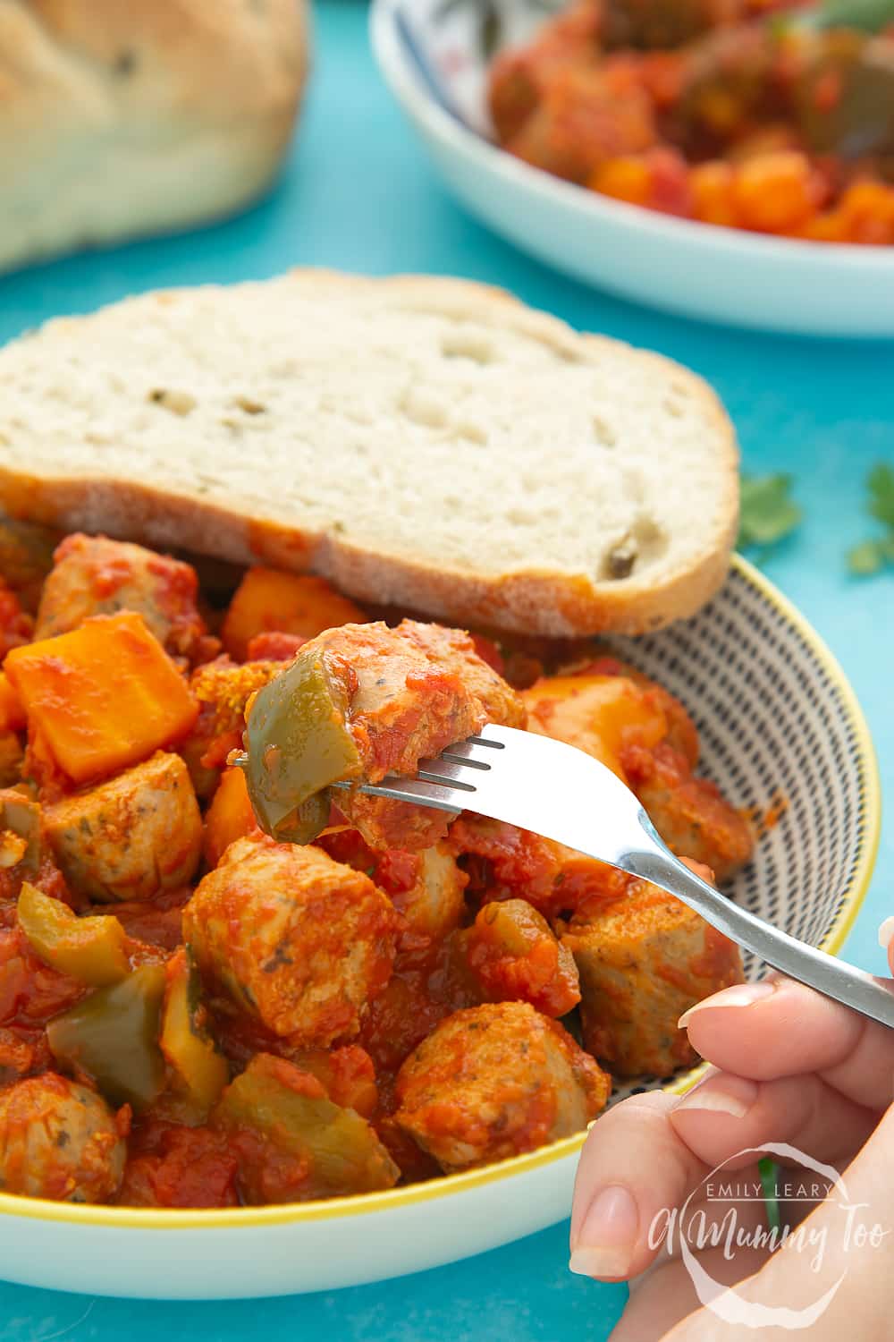 Close shot of the Slow-cooked vegetarian sausage casserole in a bowl with a crusty breadroll on the side. 