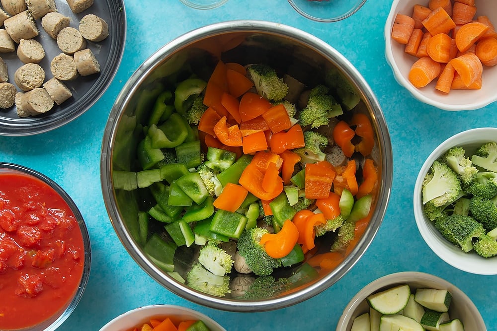 Overhead shot of the peppers both orange and green being added to the bowl for the Slow-cooked vegetarian sausage casserole. 