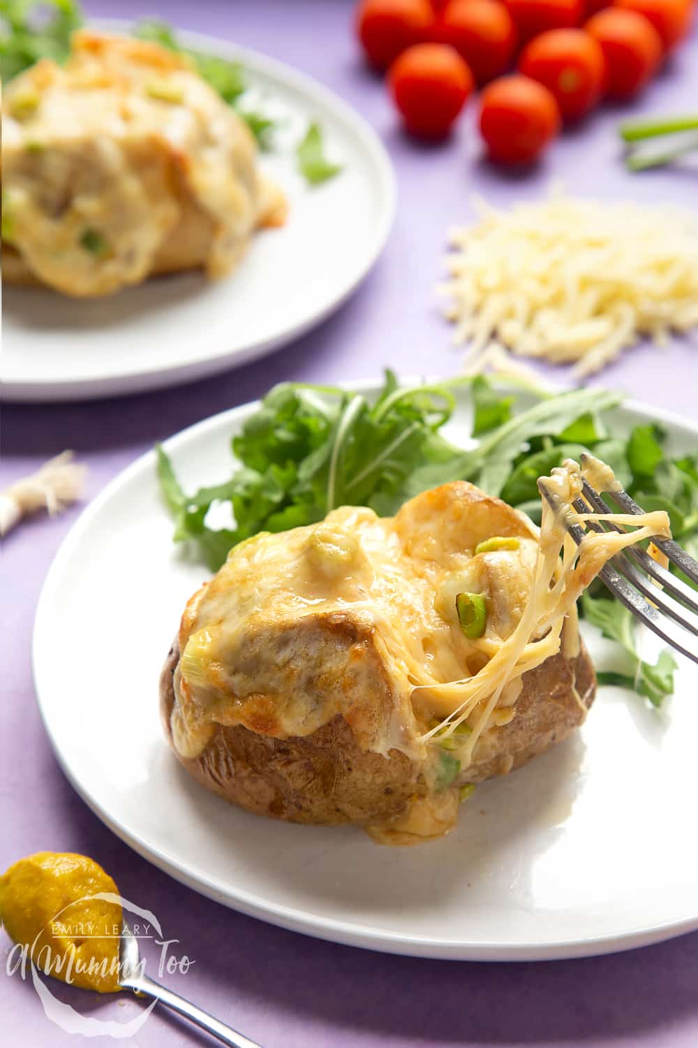 A cheese and onion jacket potato served on a white plate. A fork stretches the cheese from the potato.
