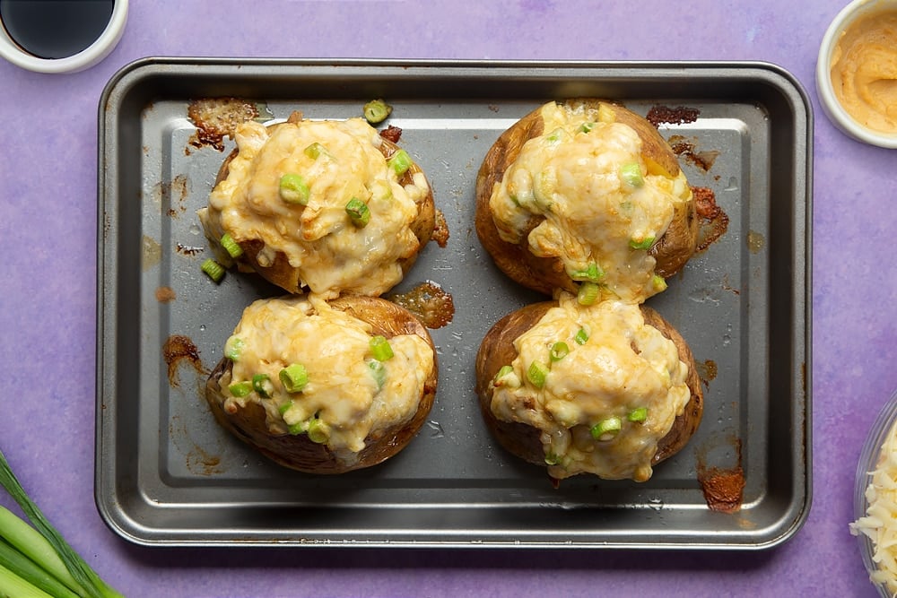 Freshly baked cheese and onion jacket potatoes on a tray.