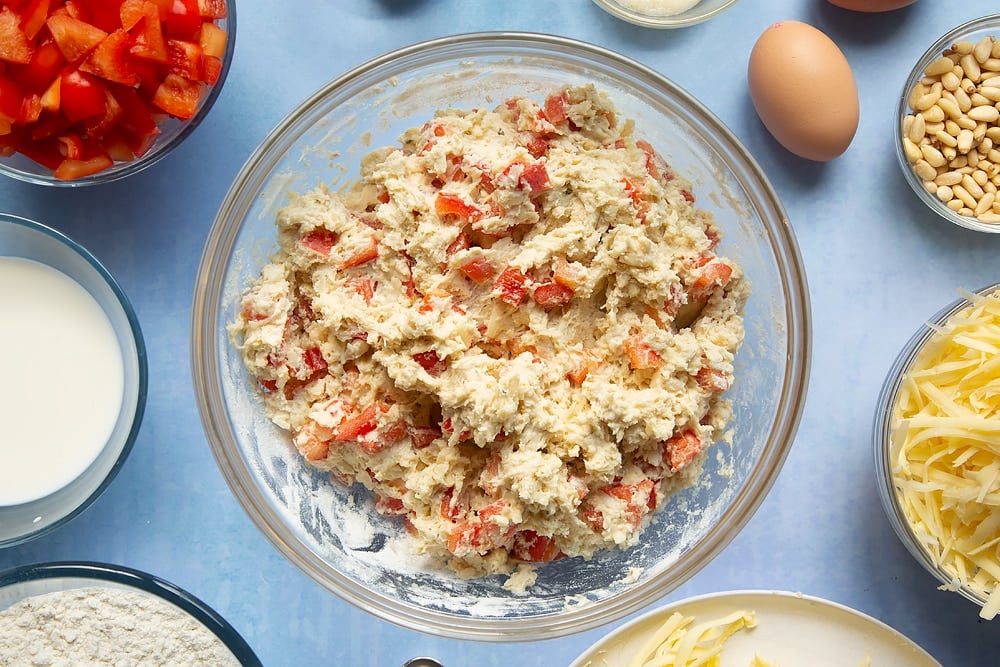 Mixing in many of the cheese and red pepper muffins ingredients in a bowl.